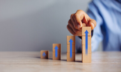businessman hand  arranging wood block stacking as step stair with arrow up.concept for business...