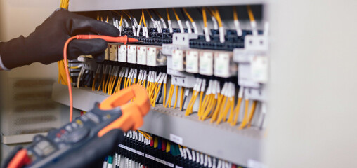 Electrician engineer work tester measuring voltage and current of power electric line in electical cabinet control.and wires on relay protection system. Bay control unit. Medium voltage switchgear.