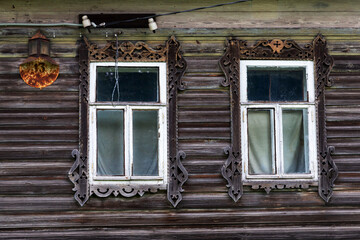 Russia, Tver region. 07.18.2020: Kalyazin. An old wooden house. Window with carved platband. Old rusty plate with house number