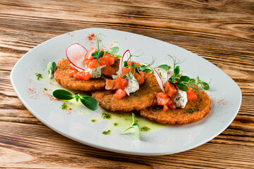 Plate with tasty potato pancakes on wooden table