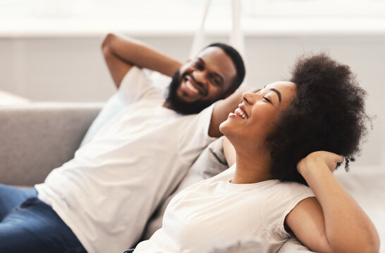 Joyful African American Couple Relaxing Sitting On Couch At Home