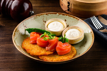Plate with tasty potato pancakes on wooden table