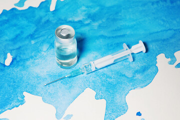 Bottle of coronavirus vaccine and syringe on world map background. Science laboratory research, vaccination concept. Coronavirus outbreak situation.