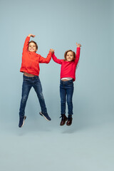 Weightless, freedom. Happy children isolated on blue studio background. Look happy, cheerful. Copyspace for ad. Childhood, education, emotions, facial expression concept. Jumping high flying