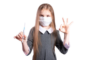 A girl in a medical mask with a syringe, shows an okay sign. Isolated on white background.