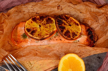 Salmon fillet fried with oranges on baking paper. Fish baked in baking paper