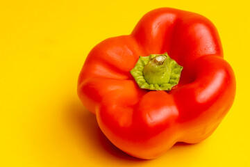 Top down view of vibrant red bell pepper or paprika. Studio food still life contrasted against a seamless dark yellow background.