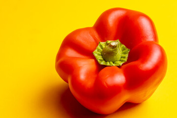 Closeup of vibrant red bell pepper or paprika. Studio food still life contrasted against a seamless dark yellow background.