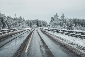 Fototapeta premium An empty, dirty winter highway. A turn on a slippery road