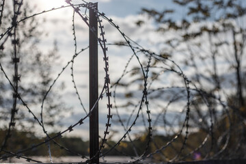 Barbed wire on the fence. The concept of prison, rescue, refugee, solitude.