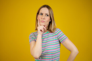 Portrait of a pensive casual woman looking away at copy space isolated over yellow background