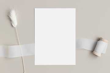White invitation card mockup with a lagurus on the beige table. 5x7 ratio, similar to A6, A5.