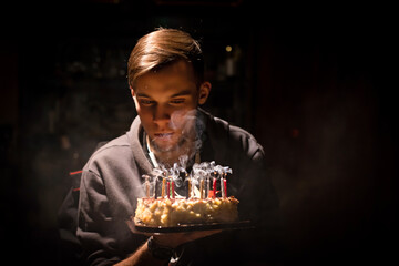young man blowing out the candles on a cake in honor of his coming of age