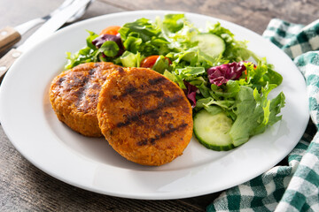 Delicious healthy chickpea burger and salad on wooden table