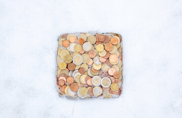 Frozen money in ice in winter snow. Euro coins, cash money frozen melt. Frozen Euro assets and financial crisis concept