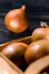 Brown onions in basket on wooden background.