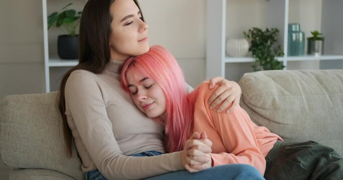 Loving gay woman caressing her girlfriend on sofa at home
