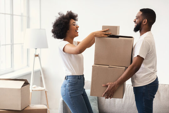 Happy African Couple Packing Moving Boxes Together Standing Indoors