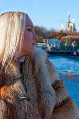 The girl in a fur coat walks around the city on a sunny day (poster mockup)