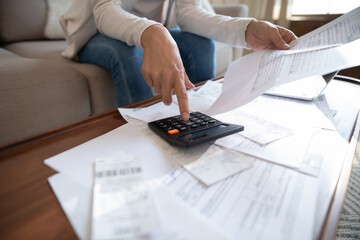 Close up busy woman using calculator, renter checking bills, planning budget, sitting at desk with financial documents and receipts, accounting expenses, calculating money, rent or mortgage payment