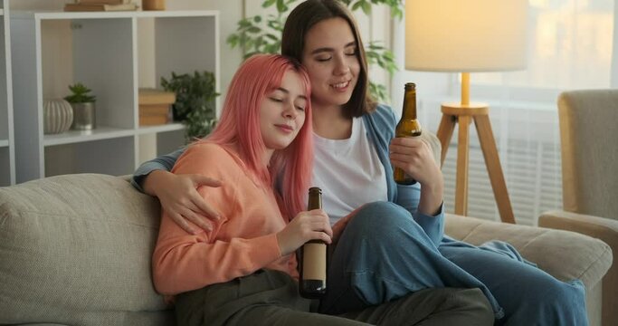 Gay woman drinking beer with girlfriend at home
