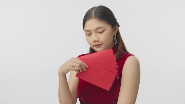 Happy young Chinese woman in traditional dress holding and waving the red envelopes using to give out money during Chinese new year, filming in slow motion on white background