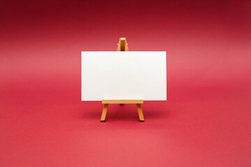 White sheet on wooden easel, isolated on red background.