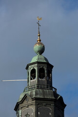 Fototapeta na wymiar Top detail of church tower Walburgiskerk rising above cityscape of medieval Hanseatic city Zutphen in The Netherlands against an ominous blue sky