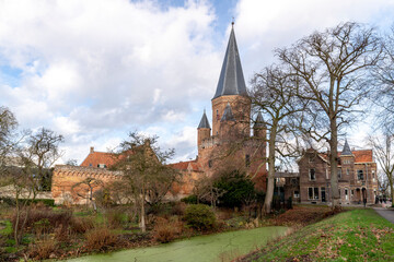 Moody view of protective canal in front of medieval city wall with the Drogenapstoren rising above the marking the Dutch Hanseatic town of Zutphen in The Netherlands against a clouded sky