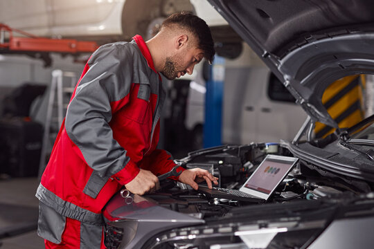 Man using laptop to fix car