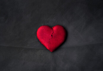 A semi-broken heart-shaped cookie. Dark background