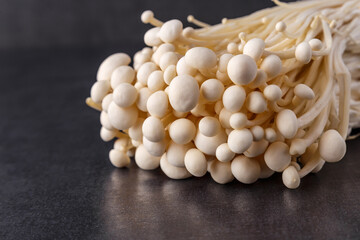 Fresh Enoki mushrooms on black background with selected focus.Enoki, also known as velvet shank, is a species of edible mushroom in the family Physalacriaceae.