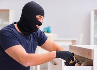 Robber wearing balaclava stealing valuable things