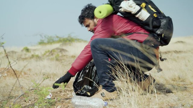 Young traveller collecting garbage or litter while hiking on mountain - concept of plogging, ecology, volunteer or social responsibility to nature