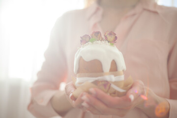 Woman hands holding traditional russian easter cake on table. The decorarion of kulich are the flower are eating on spring holiday
