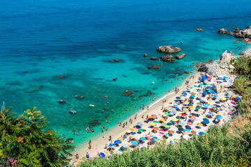 Michelino beach in Parghelia near Tropea during summertime, Calabria, Italy. Sandy beach full of vacationers and colorful umbrellas - obrazy, fototapety, plakaty