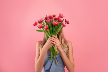 Flowers for special occasion. Anonymous young lady holding bouquet of tulips in front of her face...
