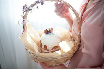 Woman hands holding traditional russian easter cake on table. The decorarion of kulich are the flower are eating on spring holiday