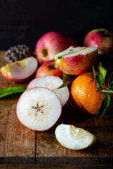 Fresh red apples, whole, and halves put on on a rustic wooden floor.