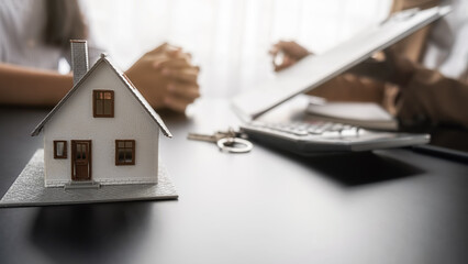 House model with agent and customer discussing for contract to buy, get insurance or loan real...