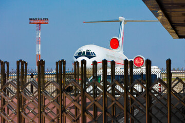A passenger plane is standing behind the fence.