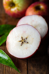 Fresh red apples, whole, and halves put on on a rustic wooden floor.