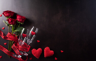 Love and Valentine's day concept made from champagne glasses , red hearts and rose on dark stone background. Top view with copy space, flat lay.