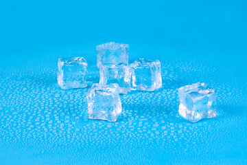 Five ice cubes for drinks with water drops on a blue background