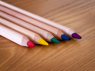 Five different coloured pencils on a wooden table