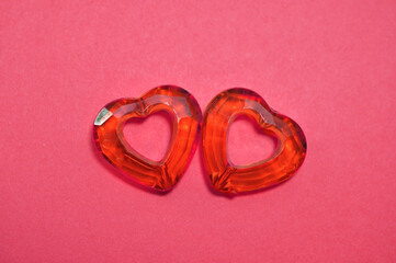 Close-up of two red glass hearts on a pink background with copy space. Valentine's day or mother's day