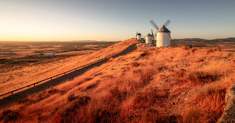 Windmills situed in Castilla la Mancha, Spain, captured during sunrise. - obrazy, fototapety, plakaty
