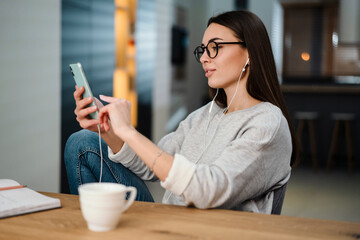 Pleased young woman listening music with earphones and mobile phone