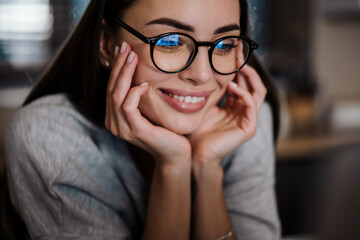 Happy young woman in eyeglasses smiling while posing at home
