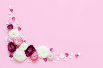 Angle  frame made of ranunculus flowers and hearts on a light pink background